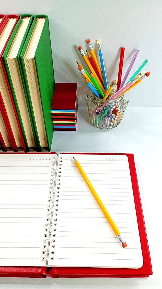 Desk with books, colorful pencils, and an open notebook.